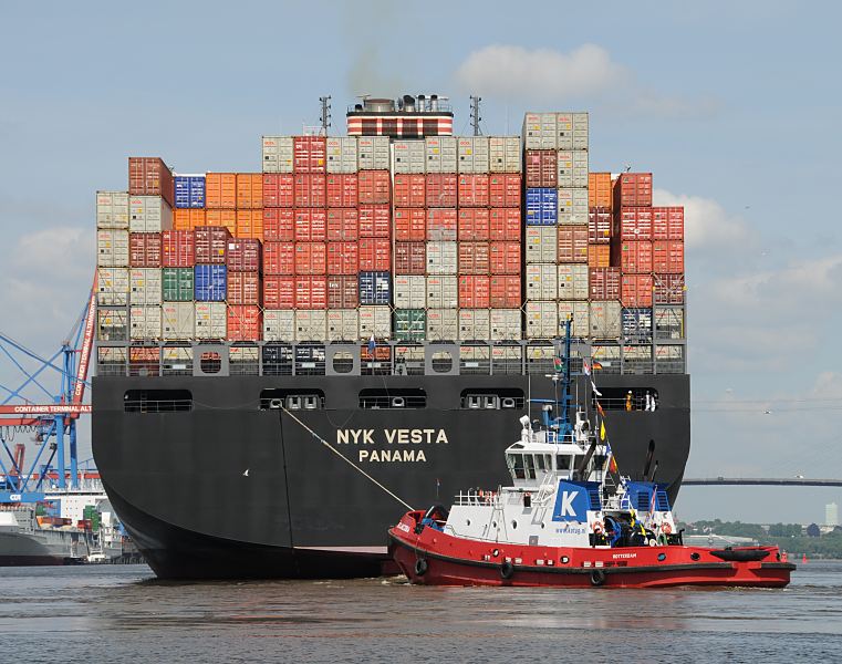 Fotos aus dem Hafen Hamburg - Schiffsheck + Hafenschlepper  011_57-8029 Das Containerschiff NYK Vesta ist hoch mit Containern beladen - ein Hafenschlepper untersttzt den Frachter bei der Ausfahrt aus dem Hamburer Hafen. Die NYK VETA hat eine Breite von 45,60m und eine Lnge von 338m. Mit 8600 TEU voll beladen hat das Frachtschiff einen Tiefgang von 14,50m und kann bei einer Maschinenleistung von ca. 87000 PS 24,5 kn fahren.  www.hamburg-fotograf.com 